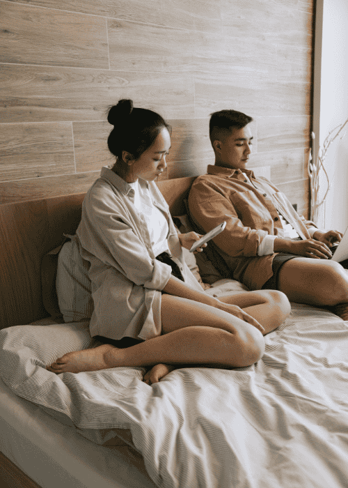Couple sitting on the bed looking unhappy, in need of couples therapy retreat
