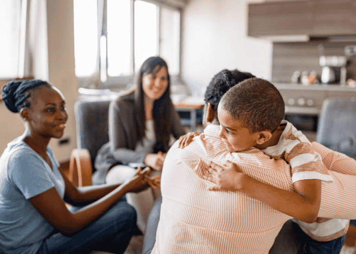 Family smiling with son hugging dad during a family therapy session